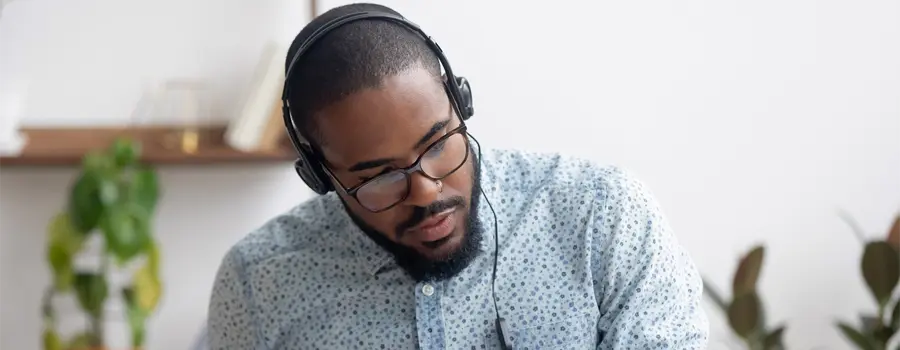 Man with headphones on taking notes