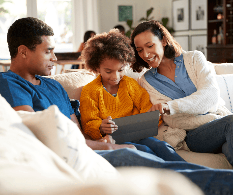 A happy family sitting on the couch and using a tablet