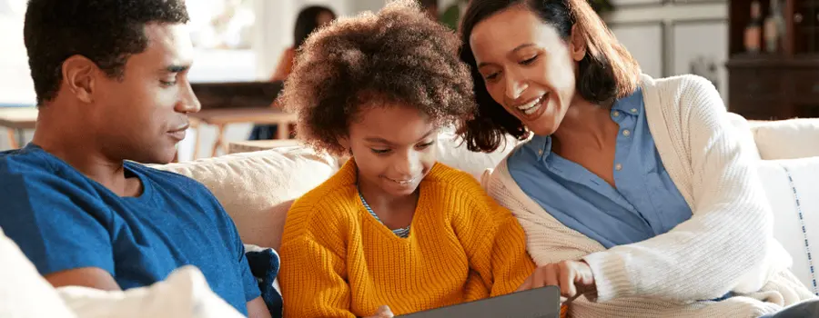 A happy family sitting on the couch and using a tablet