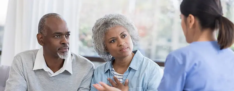 A couple sitting and listening to a medical professional speak.