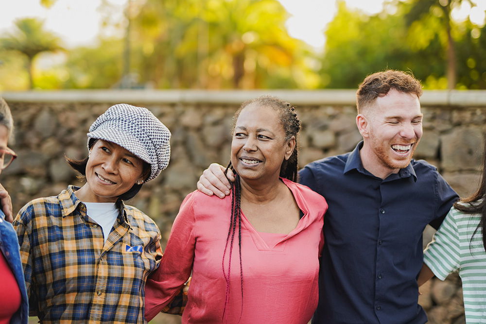 A group of people standing and smiling with their arms around each other's waists.