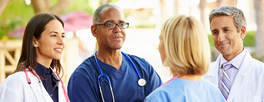 Four medical professionals speaking with each other.