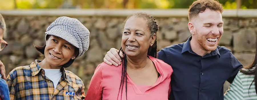 A group of people standing and smiling with their arms around each other's waists.