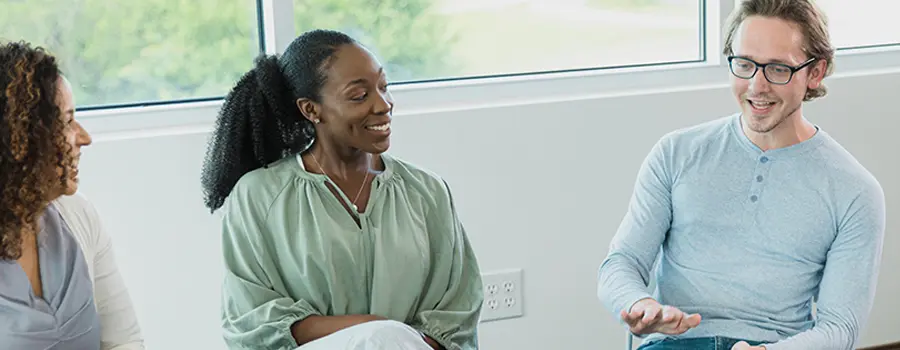 three people smiling and talking while sitting at a table
